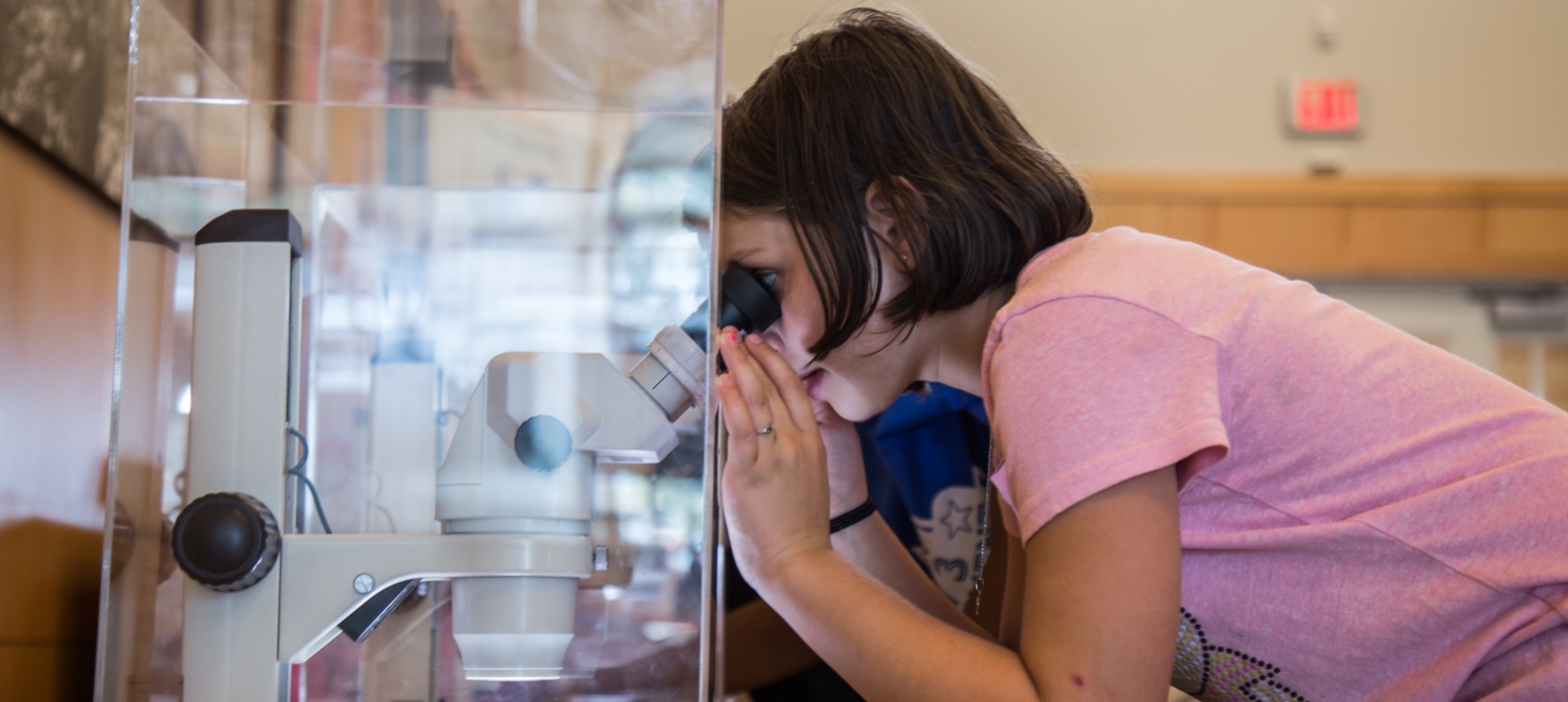 girl looking through microscope